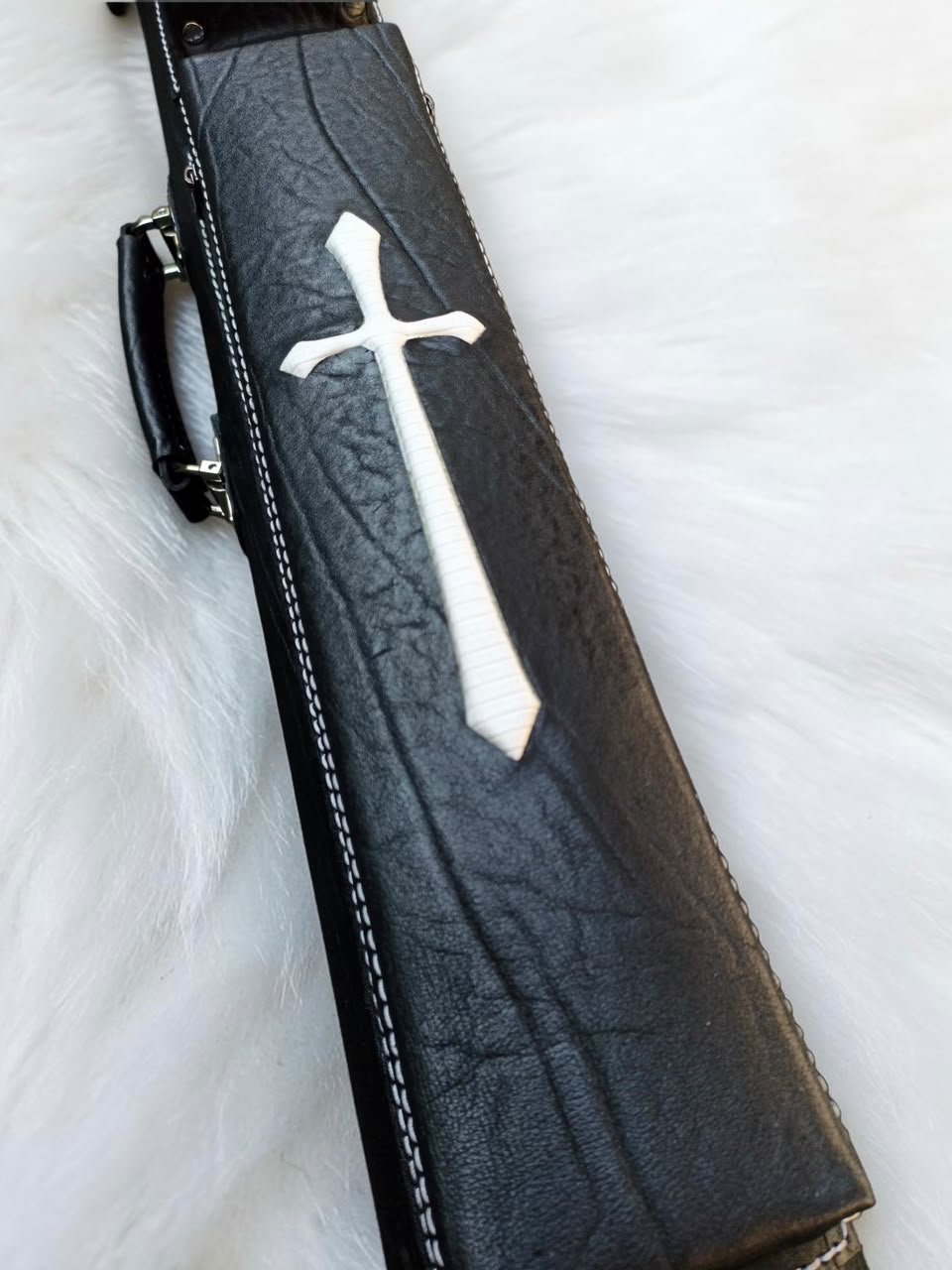 Close-up of Crusade black leather cue case with white cross inlay, textured leather, and fine stitching