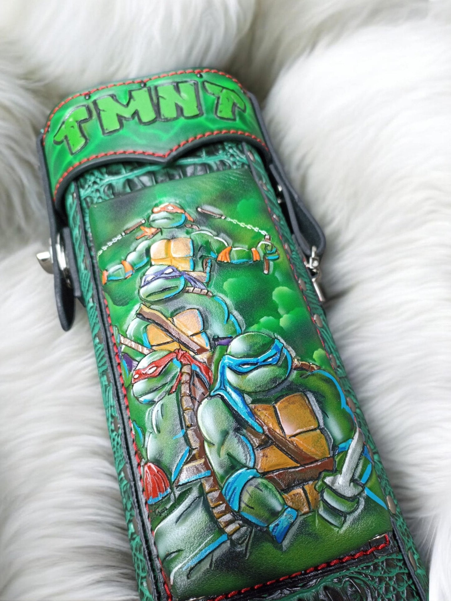 Close-up of TMNT Ninja Turtle leather cue case front with red mask detail and hand-tooled leather texture